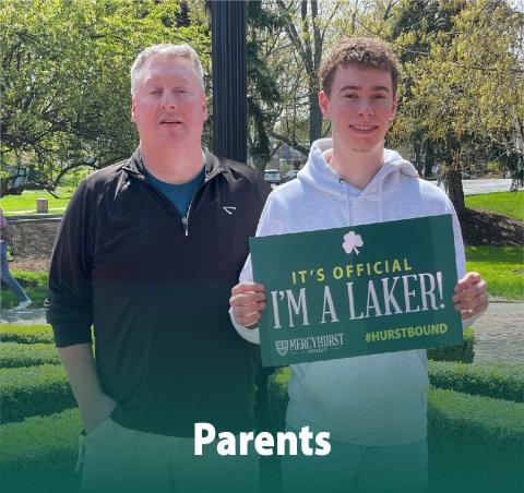 A dad posing with his son who has decided to attend Ƶ. The son holds a poster reading "It's Official. I'm a Laker!"